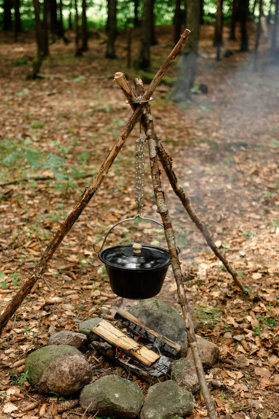 Driepoot van takken boven een kampvuur met de Espegard Driepoot Ring