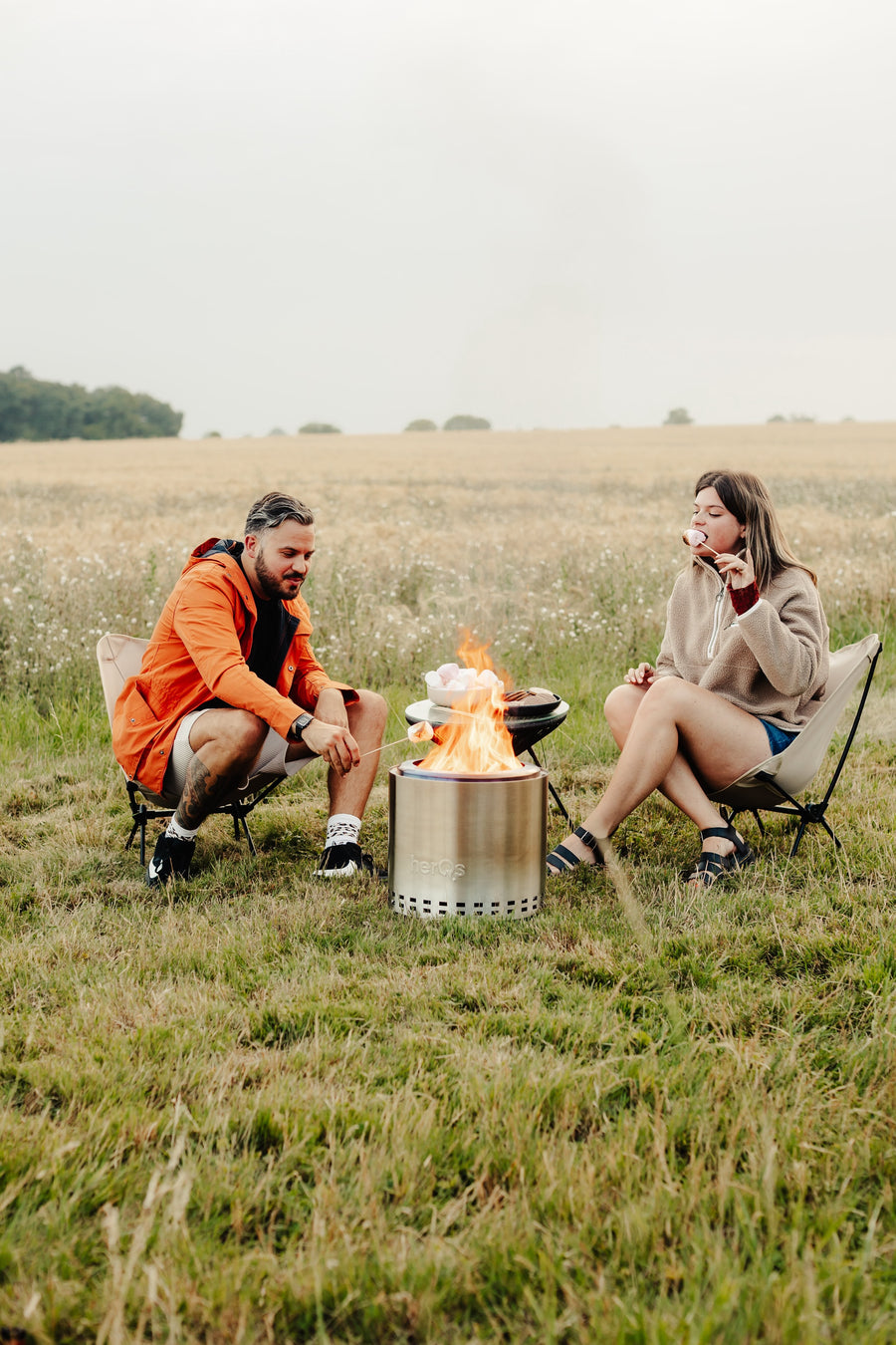Koppel geniet van herQs Cozy rookvrije vuurkorf in de natuur - marshmallows roosteren