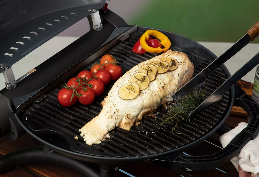 Hele vis met citroen en trostomaten op de grillplaat van de O-Grill gasbarbecue