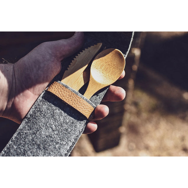 Bamboe mes en lepel van het Øyo outdoor bestek in de vilten etui in de hand