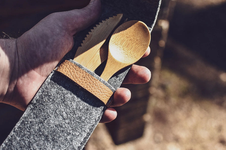 Bamboe mes en lepel van het Øyo outdoor bestek in de vilten etui in de hand