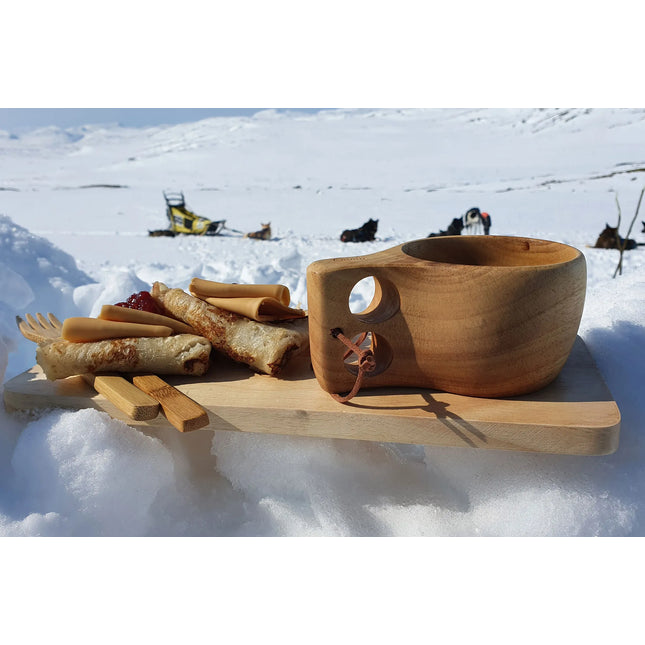 Øyo Sami Mok met pannenkoeken in de sneeuw bij hondensleeën