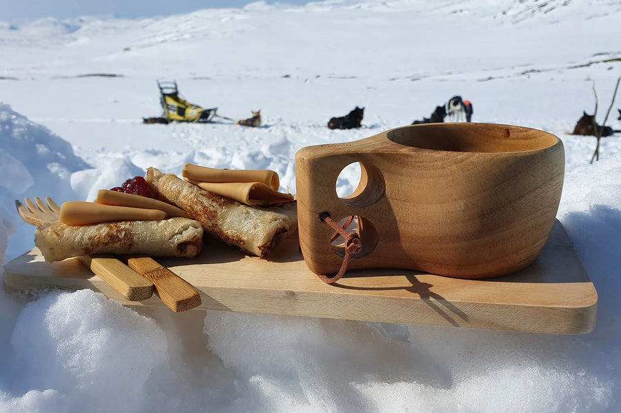 Øyo Sami Mok met pannenkoeken in de sneeuw bij hondensleeën