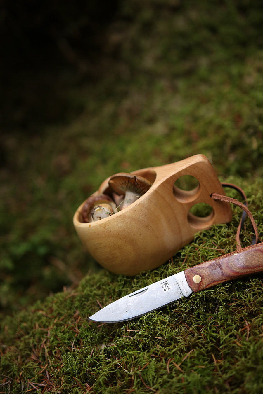 Øyo houten Sami mok met paddenstoelen op mos naast het Øyo Marka zakmes