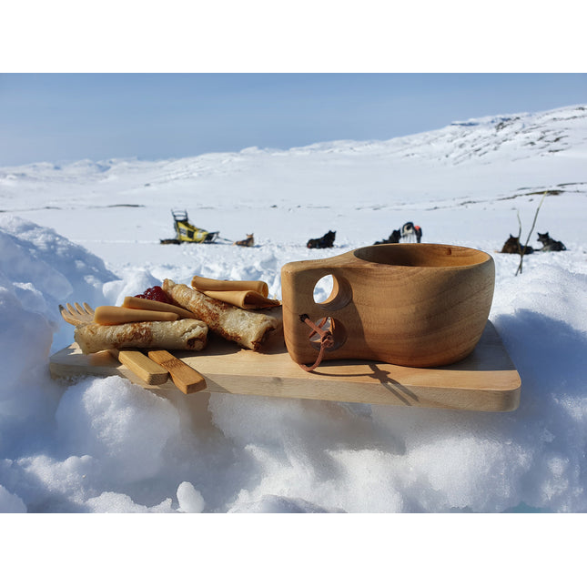 Øyo houten Sami mok op een houten plank met pannenkoeken in de sneeuw