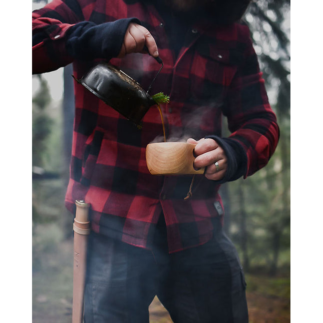 Man schenkt in het bos een drankje in de Øyo houten Sami mok