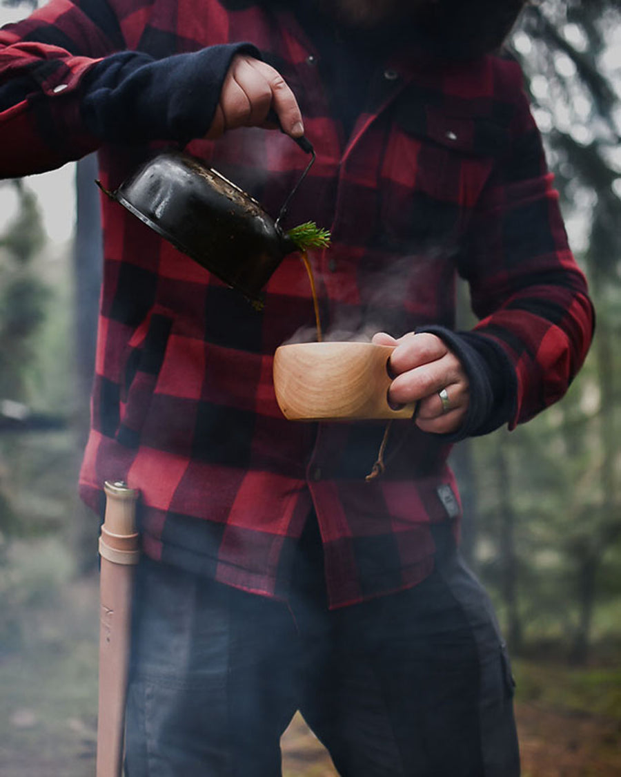 Man schenkt in het bos een drankje in de Øyo houten Sami mok