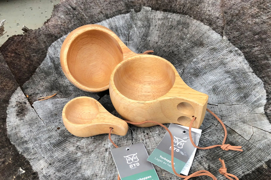 Øyo houten borrelmok naast twee houten Sami mokken op een boomstronk