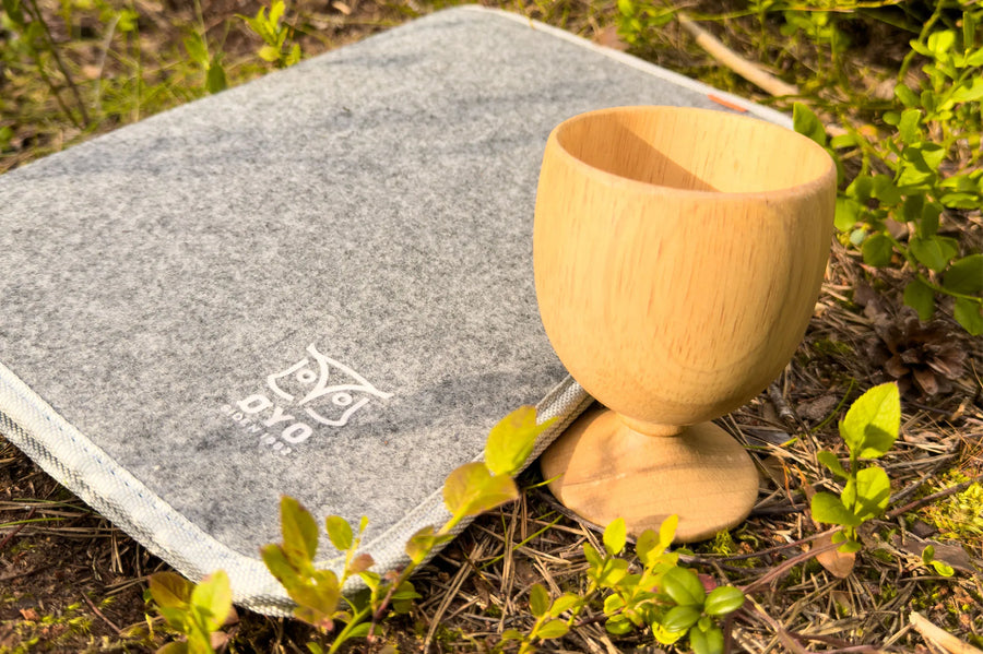 Øyo houten wijnglas op een grijs vilten zitkussen in het bos