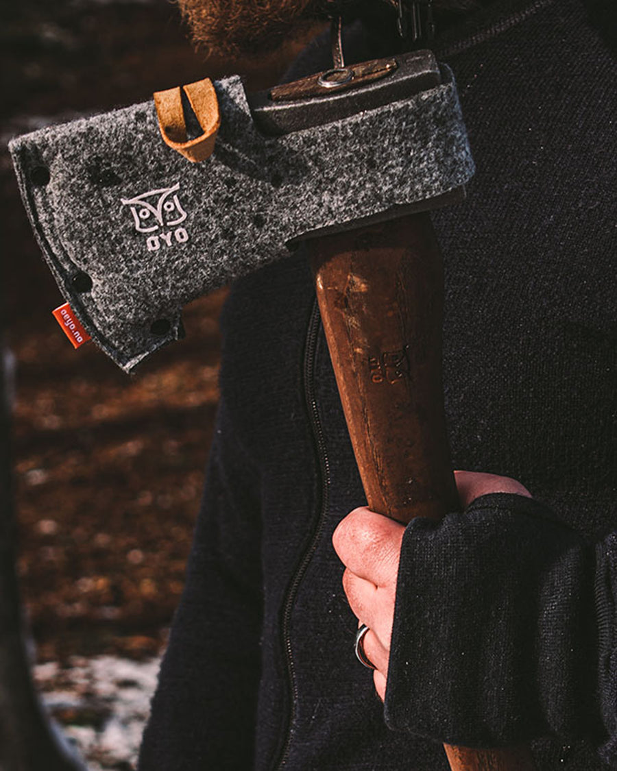 Øyo Bushcraftbijl met schede op een stapel brandhout