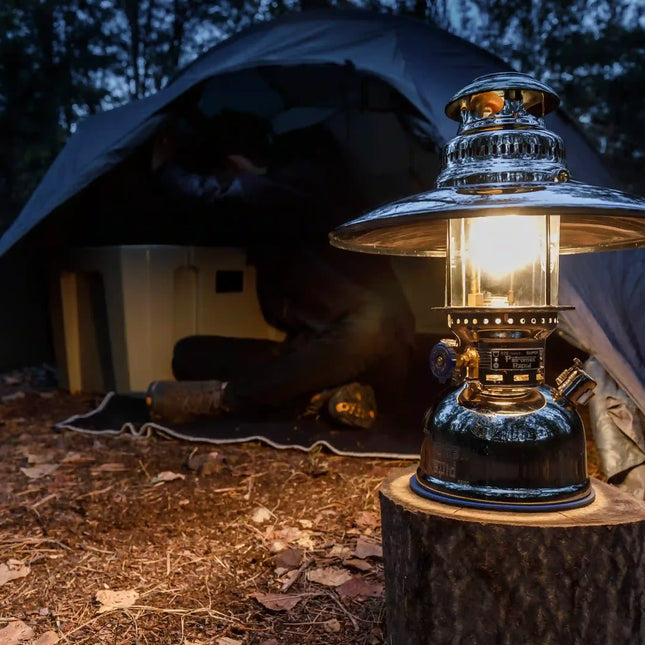 Petromax HK500 met reflectorkap op een boomstronk voor een tent