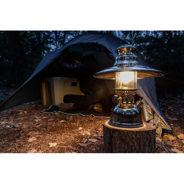 Petromax HK500 met reflectorkap op een boomstronk voor een tent