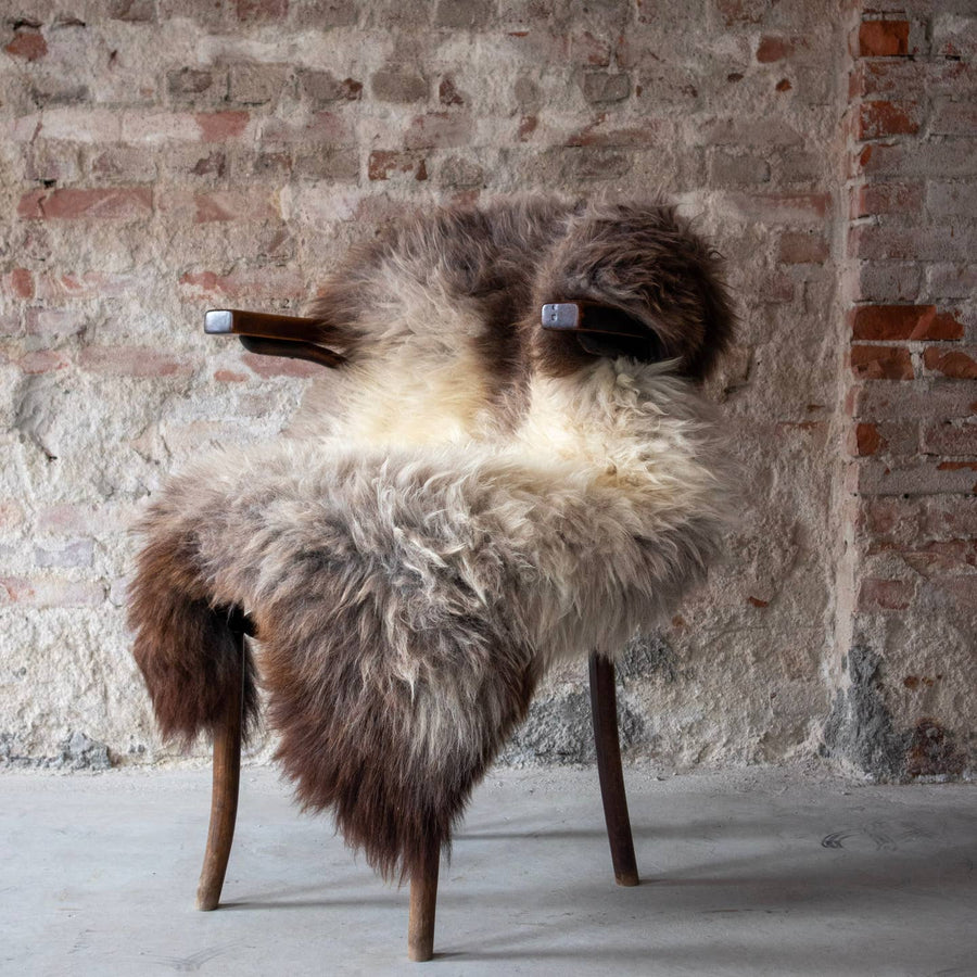Van Buren Texels schapenvacht blauwgrijs over een donkere houten fauteuil