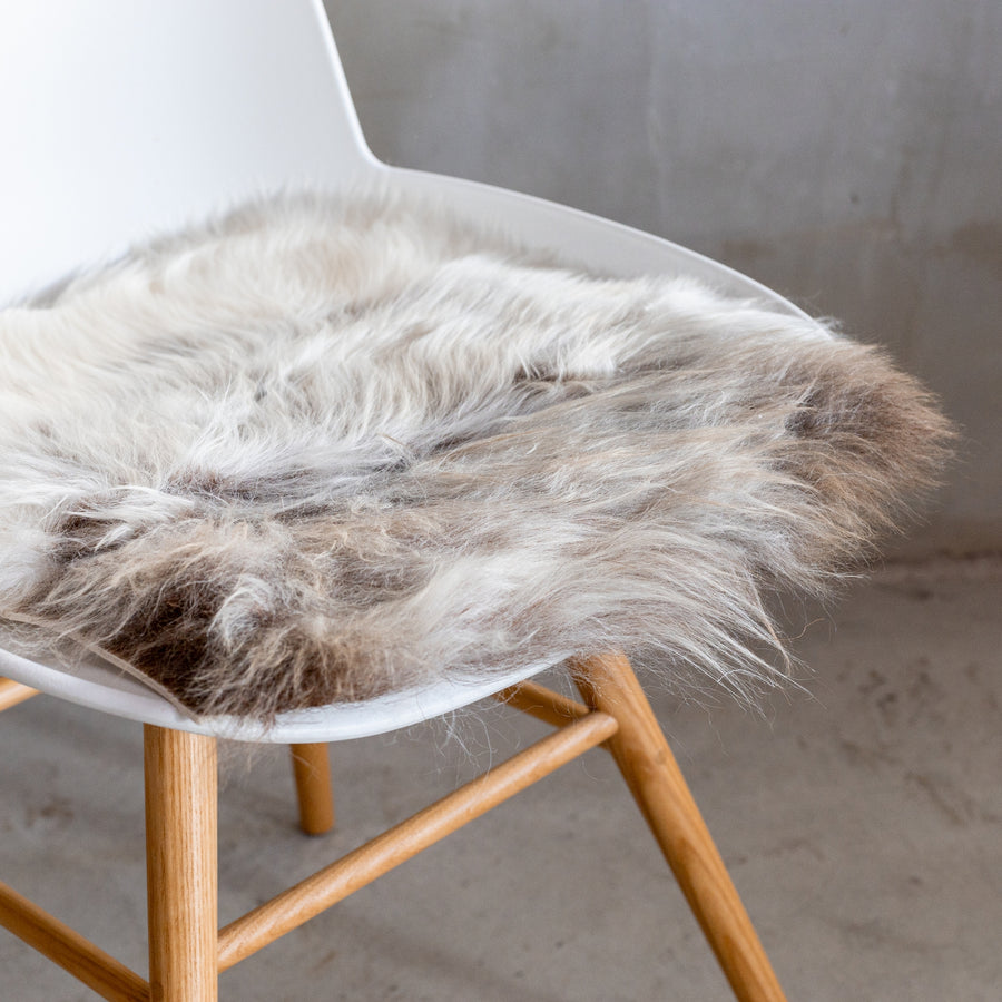 Van Buren chair pad van schapenvacht gemêleerd op de zitting van een witte stoel