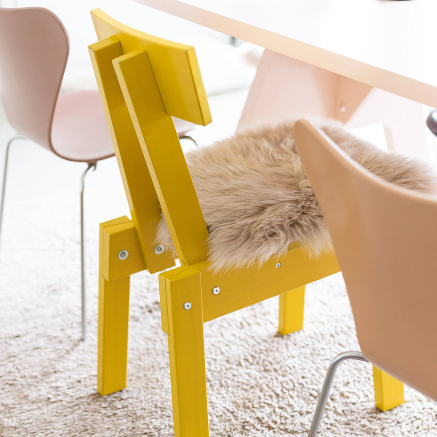 Van Buren chair pad van schapenvacht linnen op een gele houten eetkamerstoel