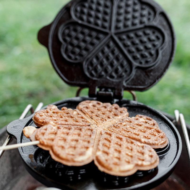 Ronde wafel met hartjesmotief in het geopende wafelijzer boven de Atago