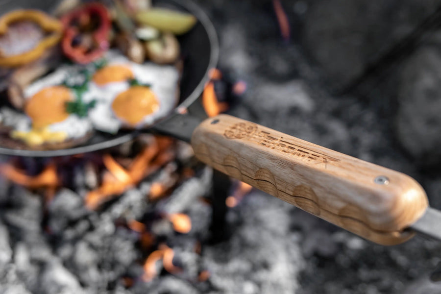 Petromax smeedijzeren pan met magnetische houten steel boven kampvuur